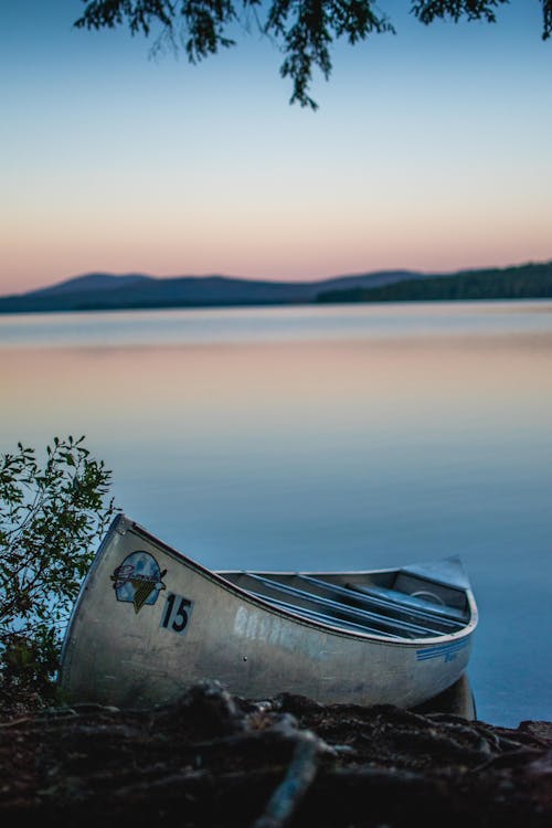 A rowboat on a serene lakeside with the hills of Northern New Hampshire in the background