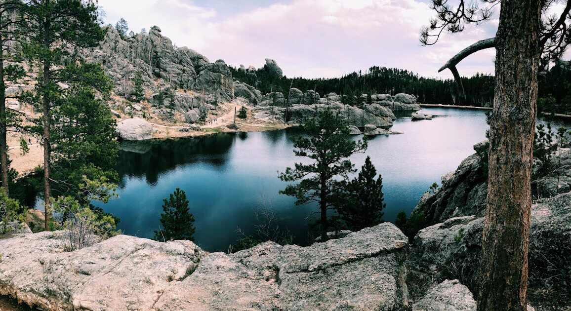 Serene creek and rock outcroppings underneath a partially cloudy sky in Custer, South Dakota