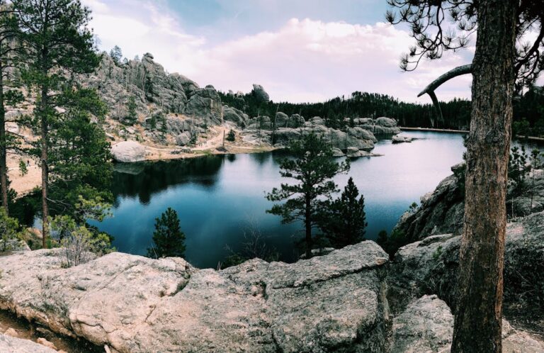 Serene creek and rock outcroppings underneath a partially cloudy sky in Custer, South Dakota