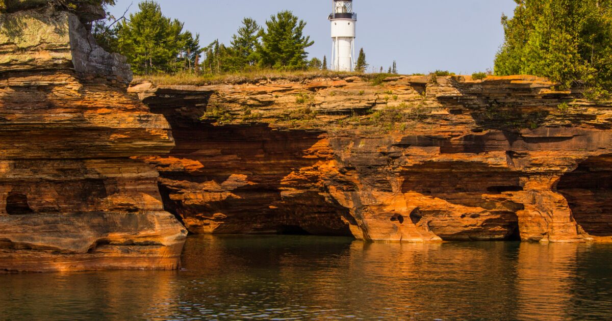 A lighthouse on a cliff above a body of water.