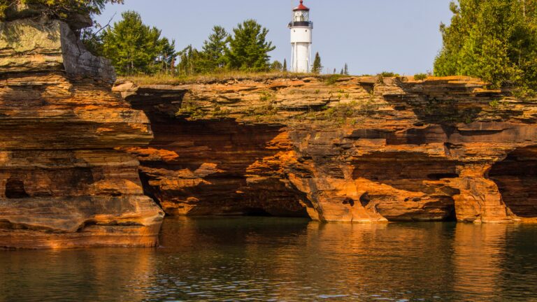 A lighthouse on a cliff above a body of water.