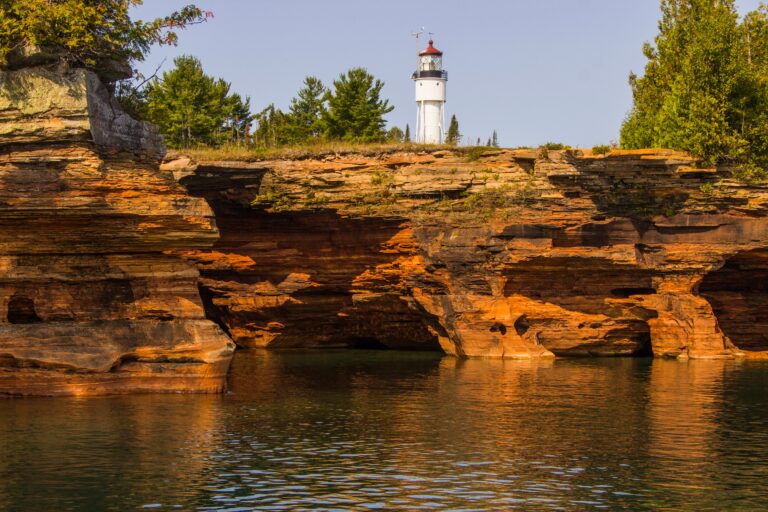 A lighthouse on a cliff above a body of water.