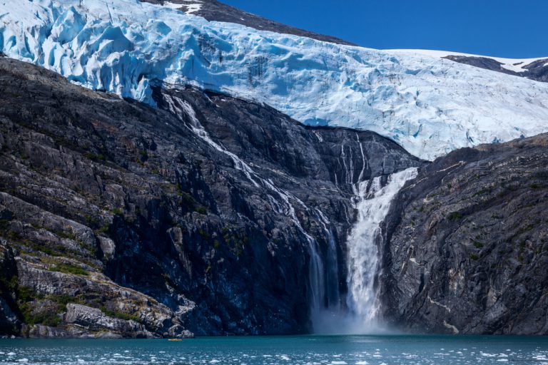 A kayaker paddles among ice burgs in Blackstone Bay to view the melt-water falls of Northland Glacier