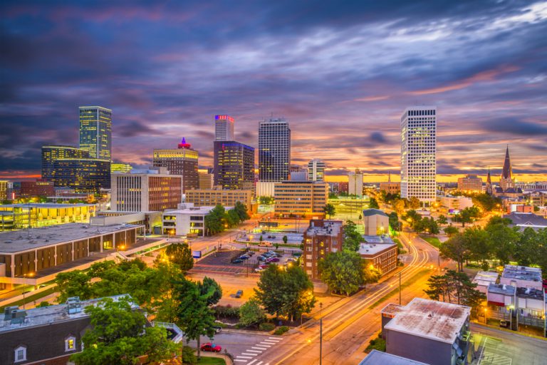 A cityscape at twilight dotted with trees under a purple sky.