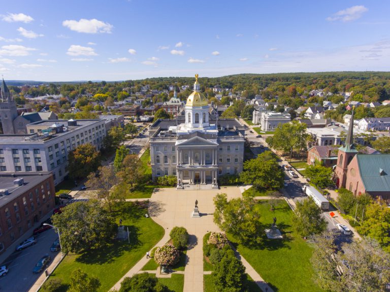 A grassy area dotted with trees in front of a gold-domed building surrounded by modern and historical structures.