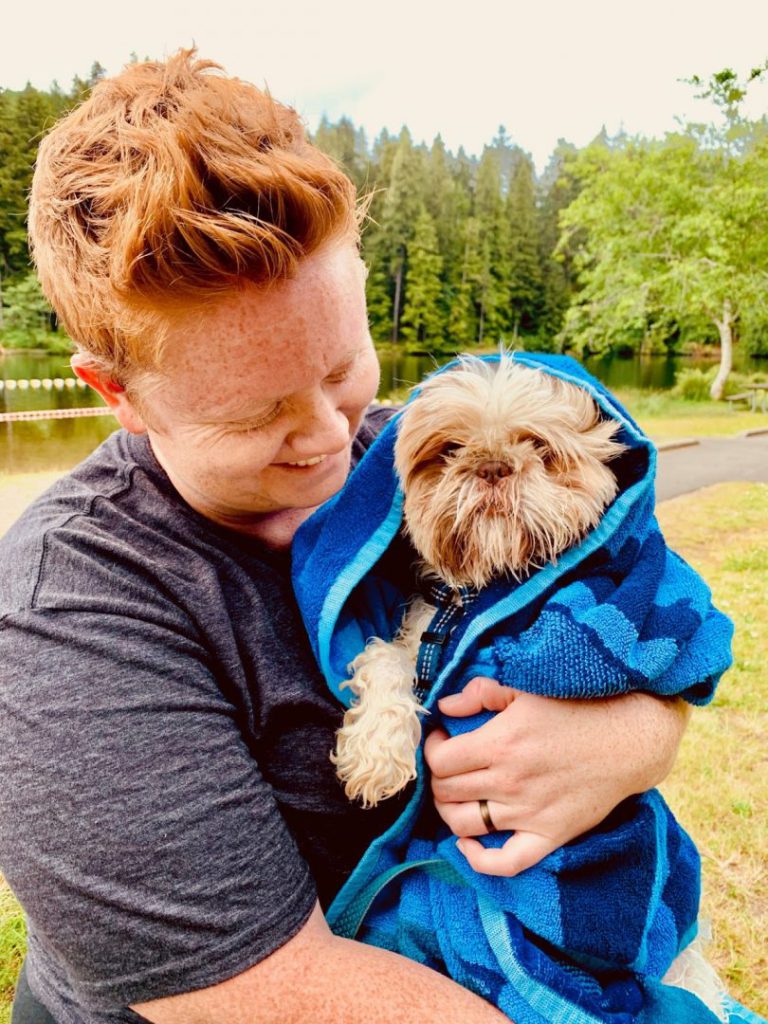 Woman holds her shih tzu wrapped in a towel