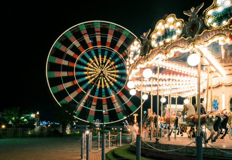 A Ferris wheel and carousel light up and spin at night at a Colorado amusement park