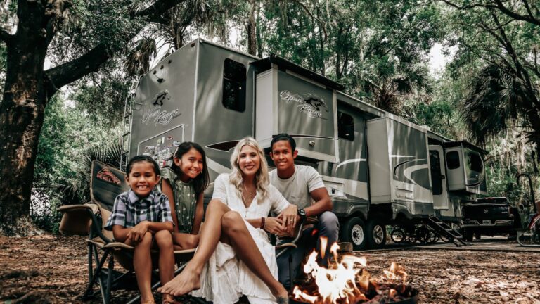 family sitting around a fire in front of an RV