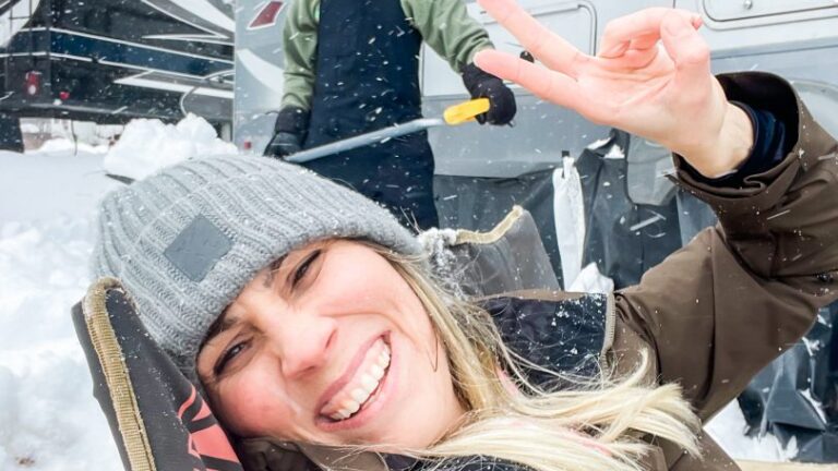 woman smiling in front of an RV on a snowy day