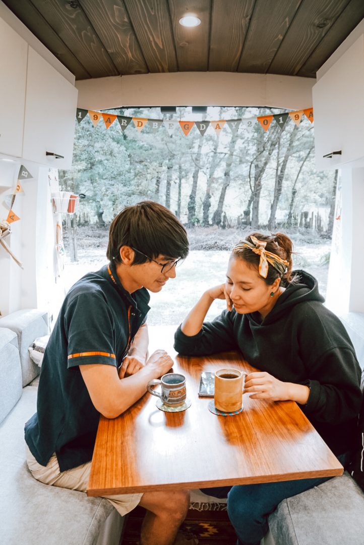 man and woman sitting in an rv looking at a phone