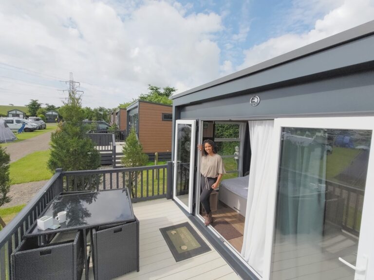 Young woman stands in the opening of the back door of a tiny house