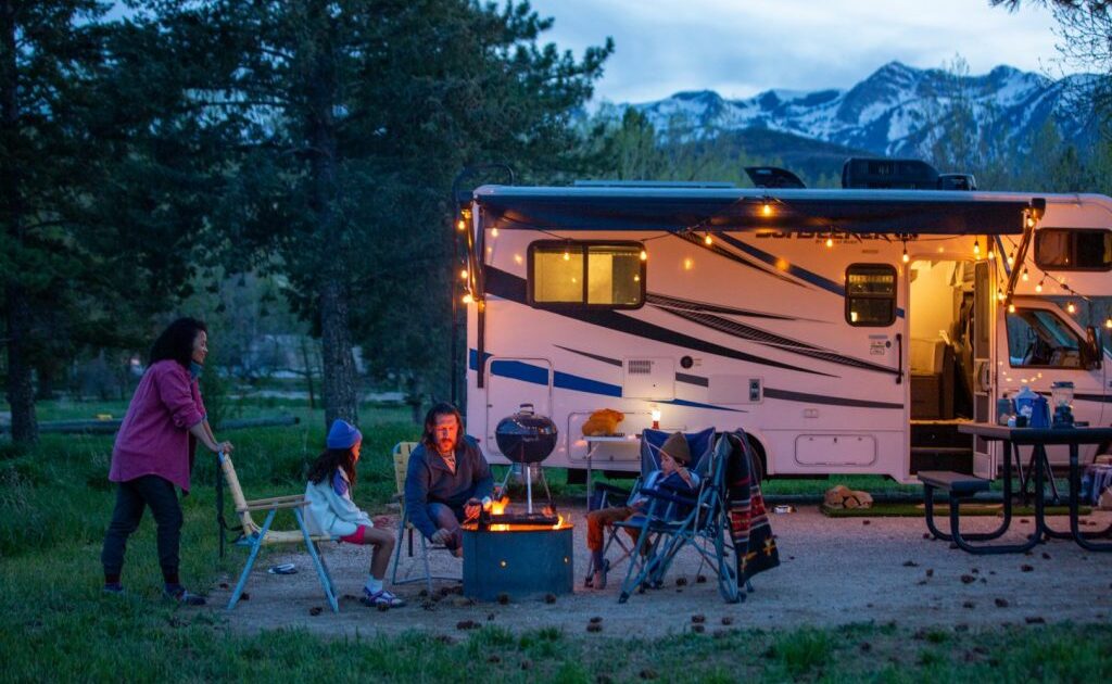 family relaxing outside a trailer at dusk