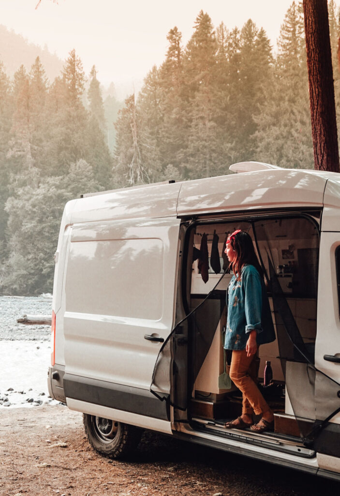 Woman stands at the open door of her camper van