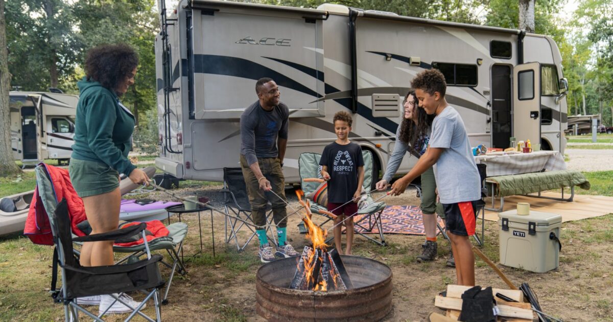 family at an rv park standing around the campfire