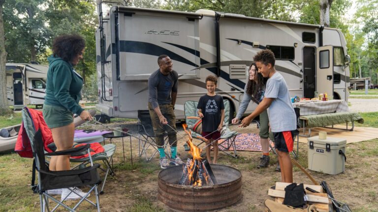 family at an rv park standing around the campfire
