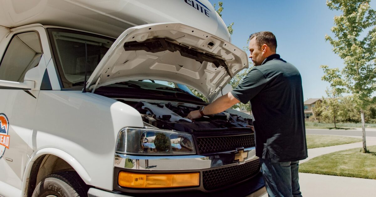 man working under the hood of an rv