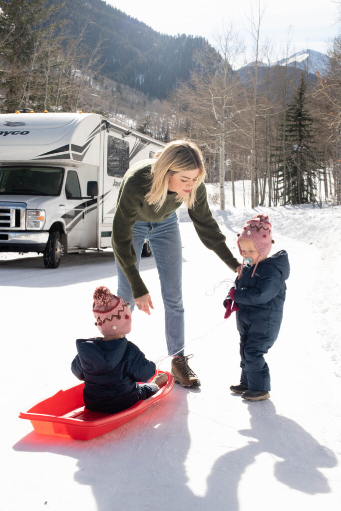 RV in snowy area where mom & kids are sledding