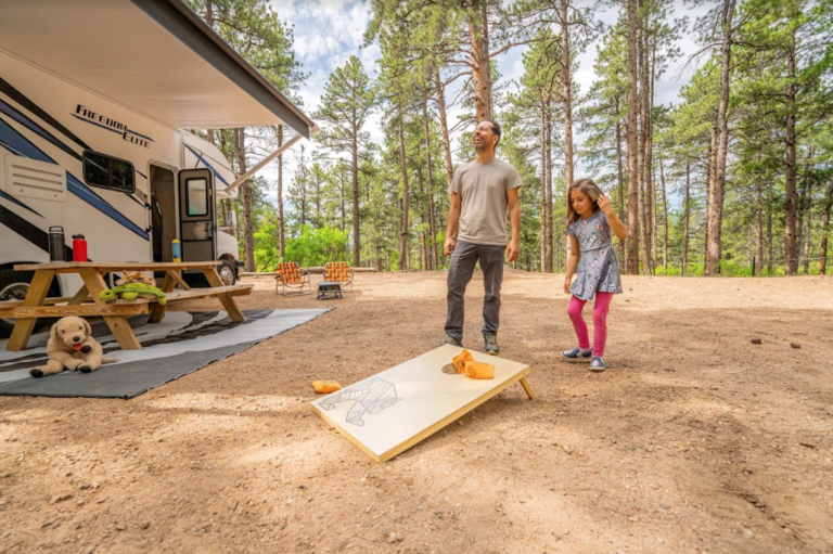 A family playing cornhole in front of their RV