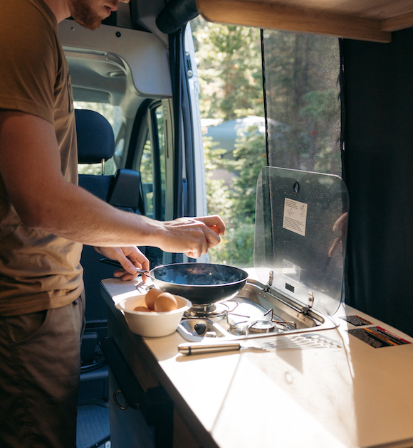 A man cracking eggs for breakfast in an RV kitchen