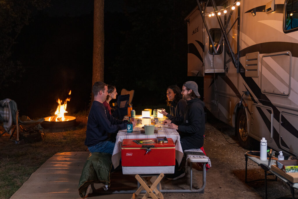 a family outside with lights strung next to an RV