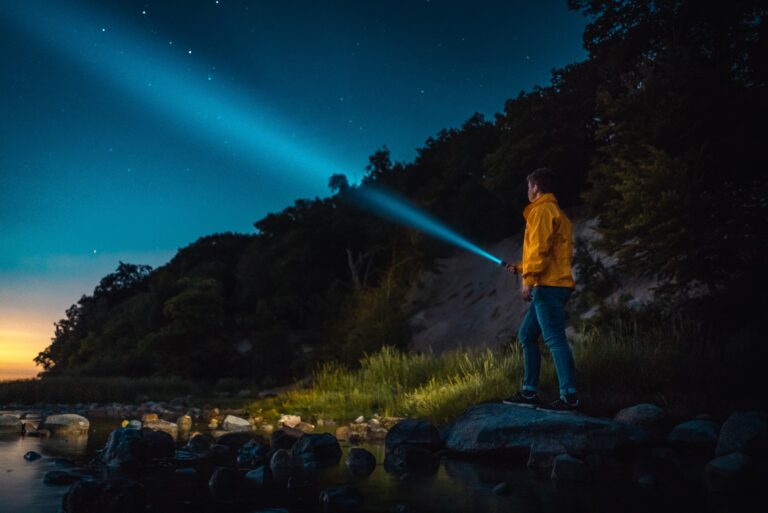 A man holding a flashlight in a dark wilderness area