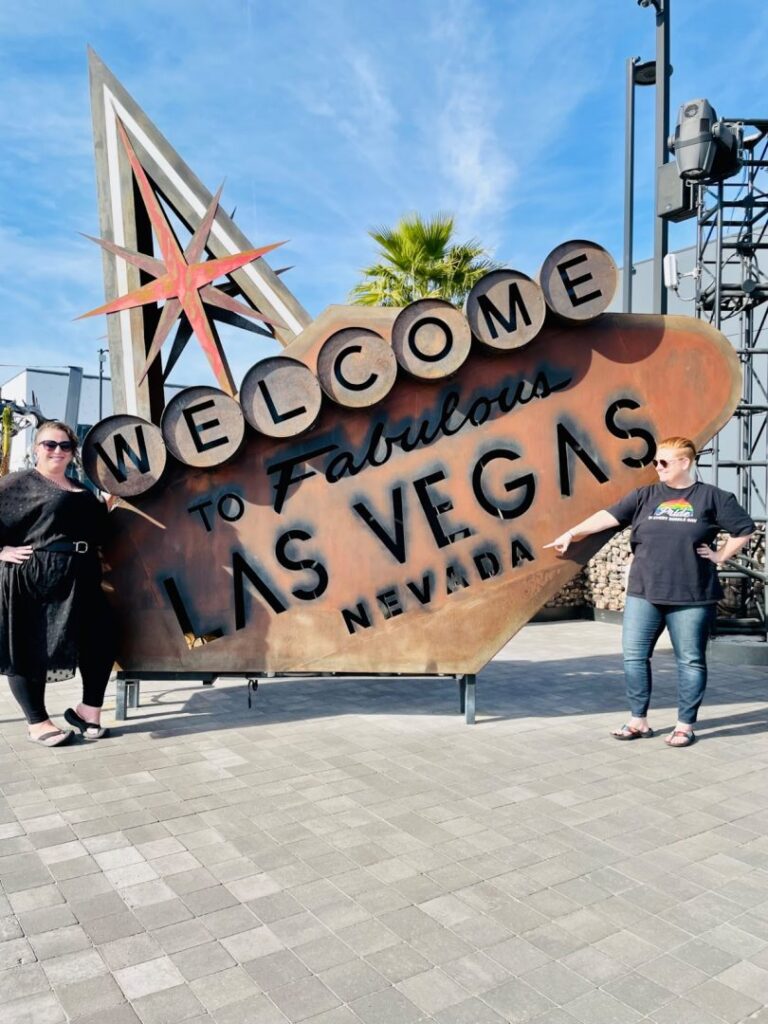 Couple pointing to a 'welcome to las vegas' sign