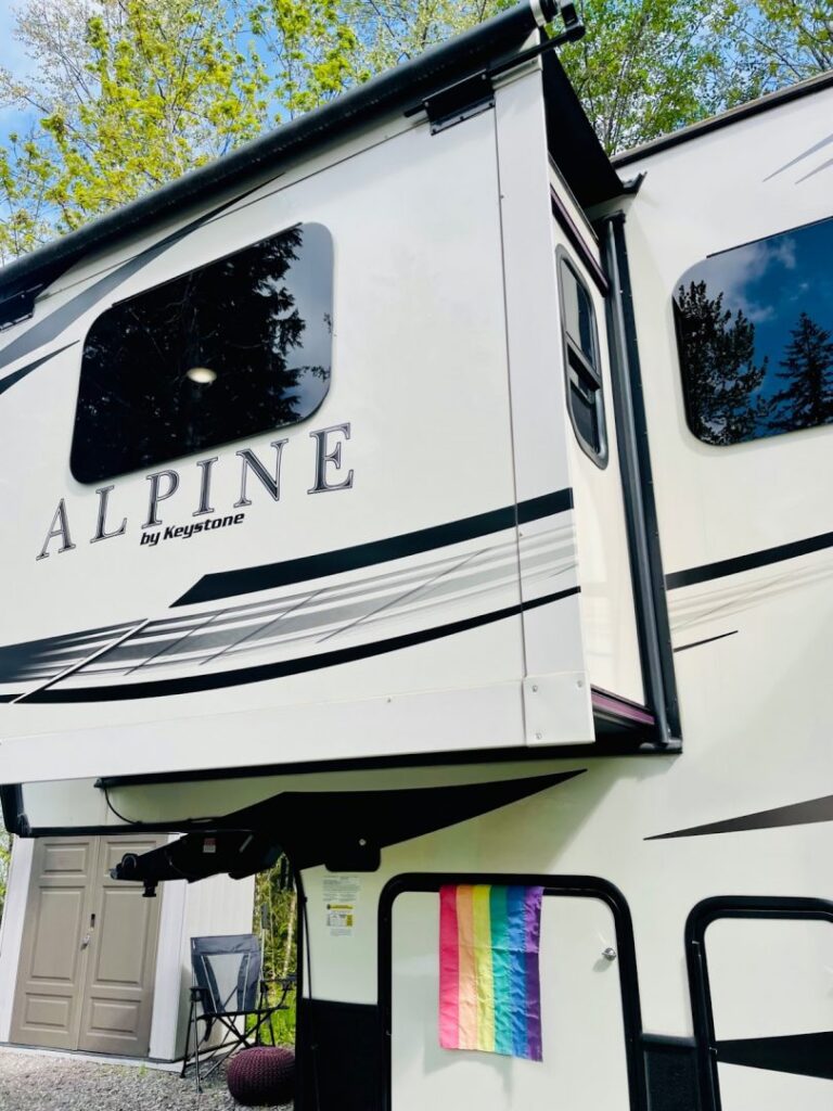 Fifth wheel trailer with slide out extended and pride flag pinned up