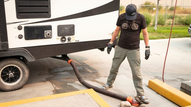 A man holding his RV sewer hose in place while it empties