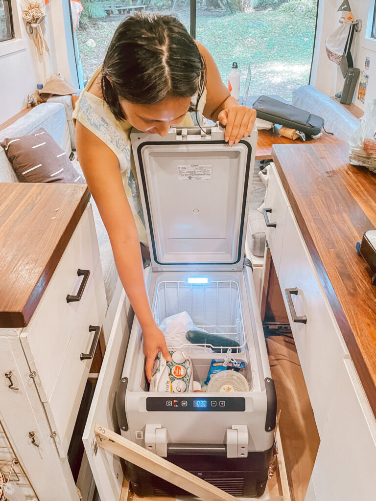 Woman reaches into the fridge of her campervan