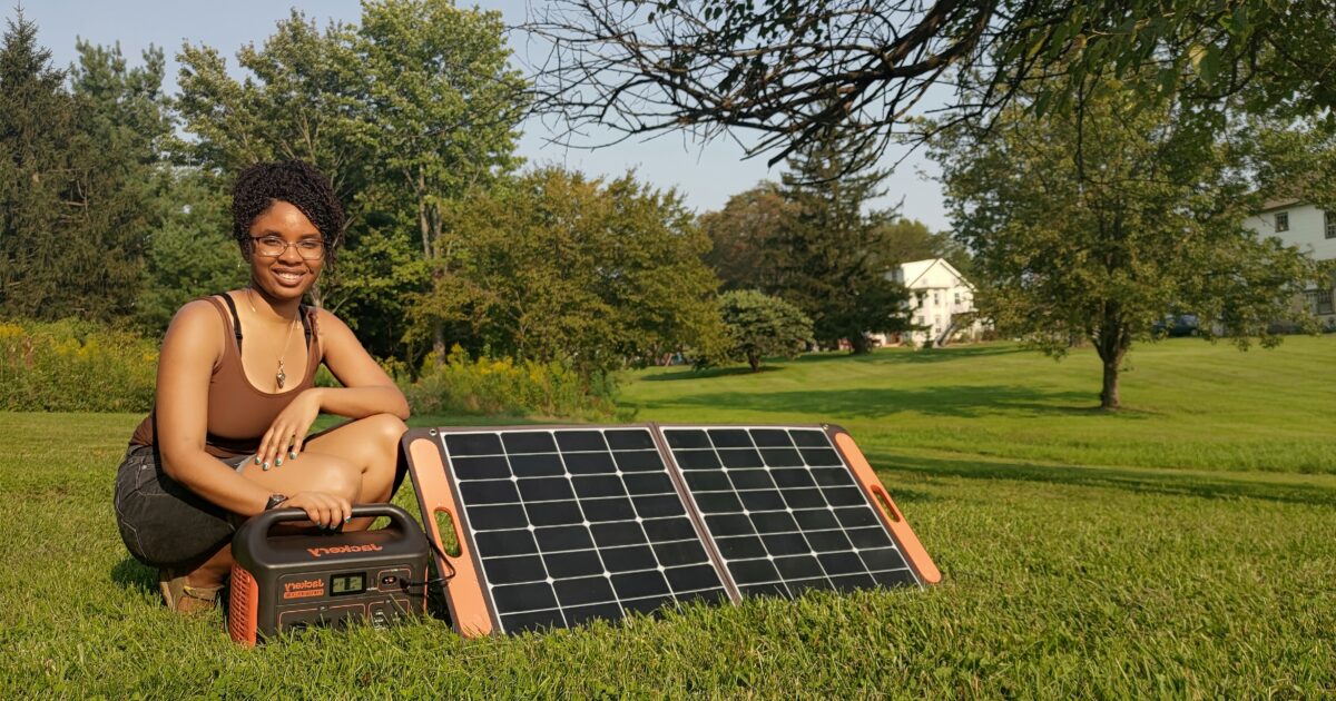 Woman poses next to solar panels
