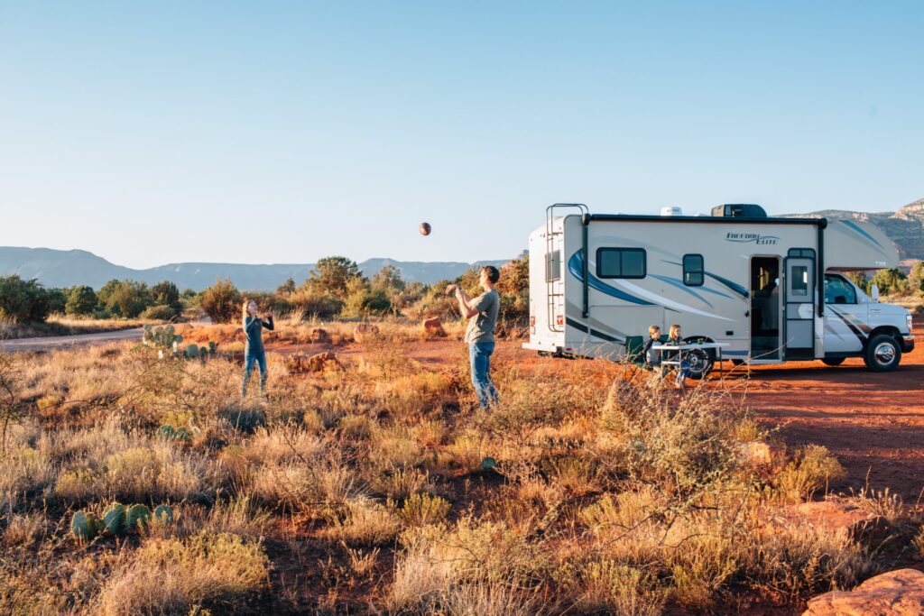 Dad and son playing catch in front of motorhome