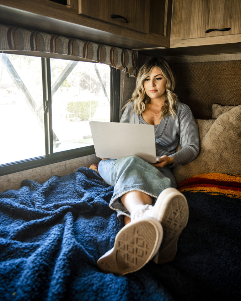 woman sitting on bed in an rv with her laptop