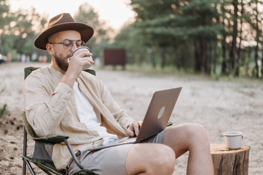 Man using RV apps on computer in campground