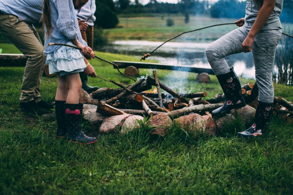 Camping basics for kids: parents teach daughter fire safety around a campfire