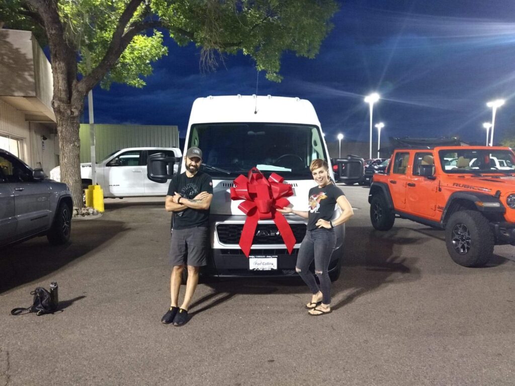 couple in front of van in the dealership