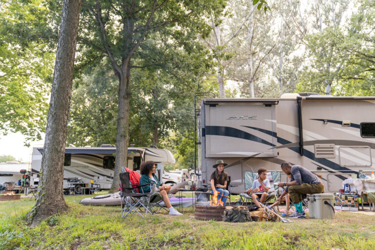 a camper at a campsite with a family by the fire