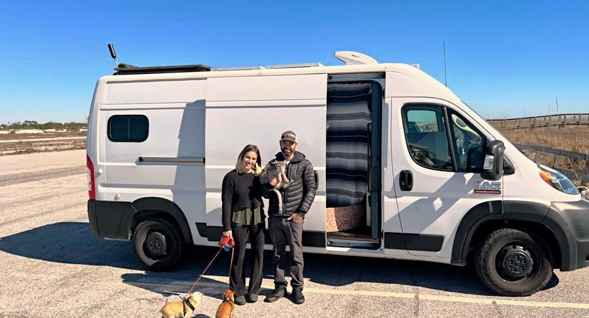 couple with dogs in front of campervan