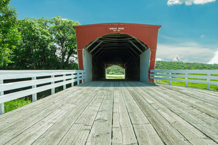 Low Angele looking inside of Hogback Covered Bridge in Madison County, Iowa, with trusses, running boards, and light at the end of the tunnel
