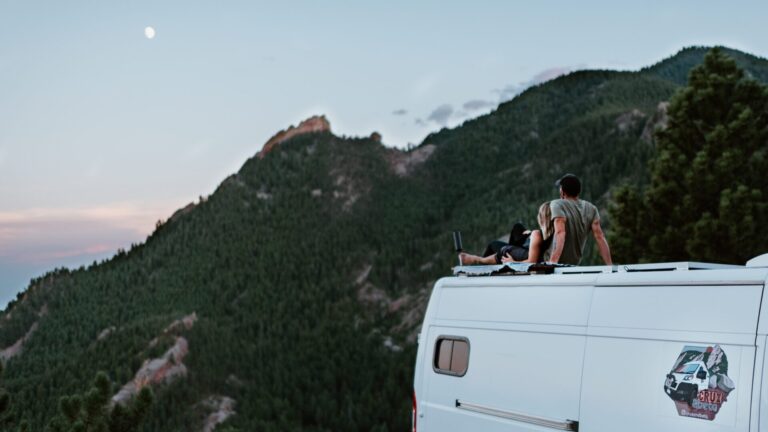 a couple on the rooftop of a van watching the moon and mountain environment