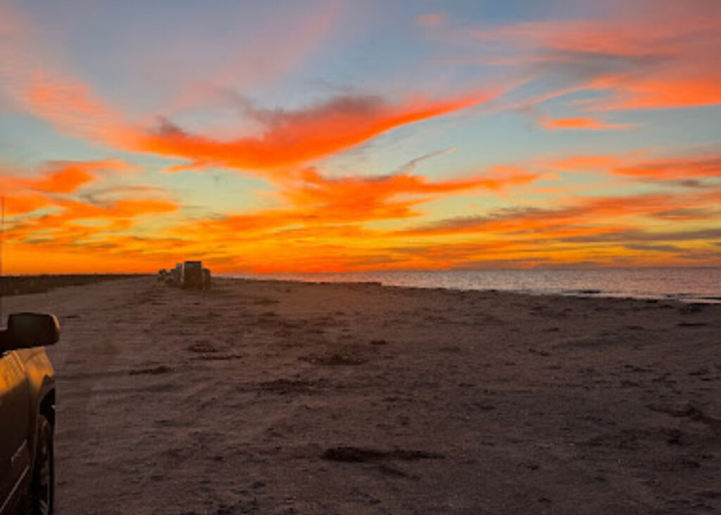 RVs boondocking at the beach during sunset.