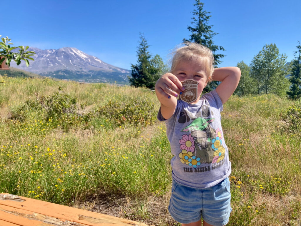 Little girl holding up Junior Ranger badge at Mount St. Helens