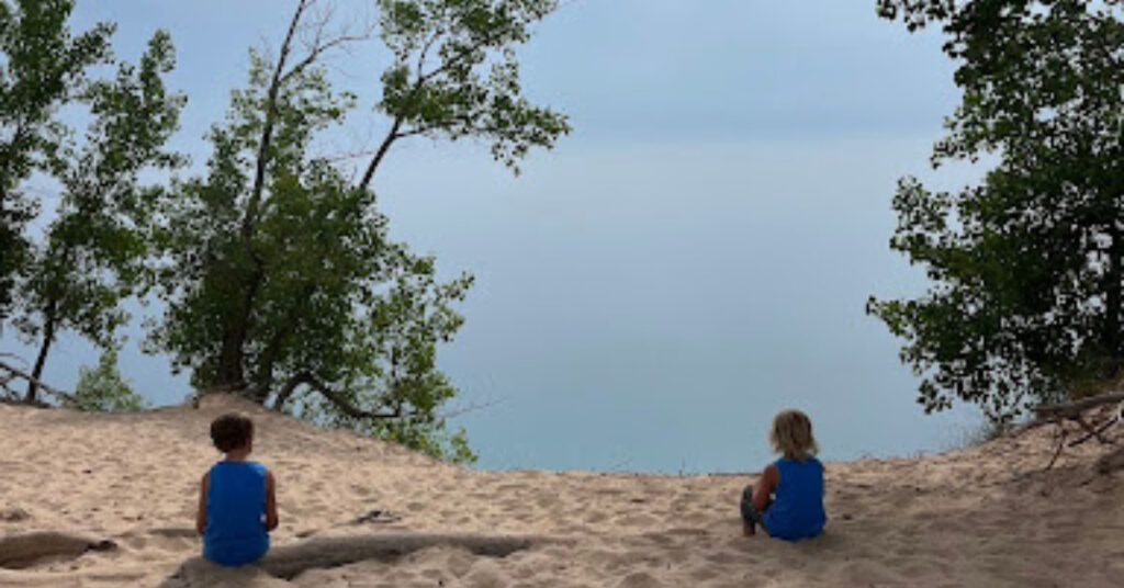 Boys looking out at Lake Superior sitting on a dune  part of great lakes rv trip