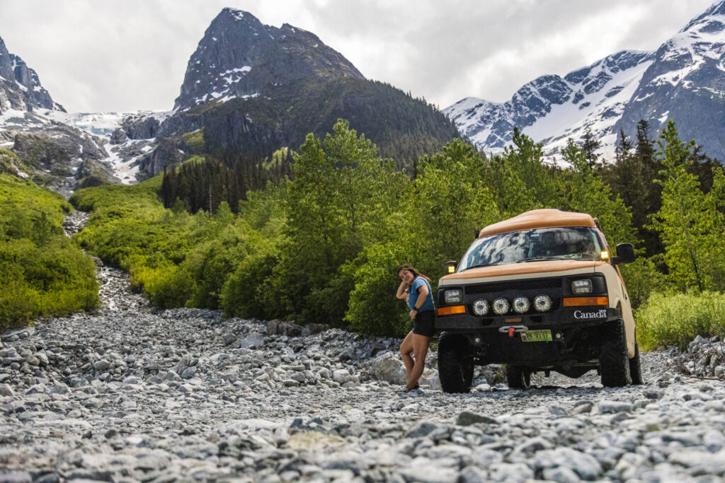 woman standing next to van in the mountains 