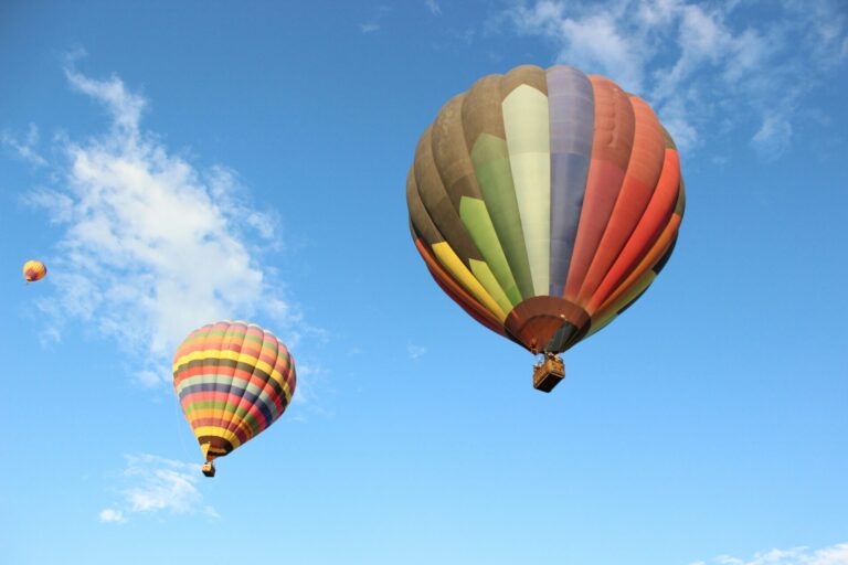 Two colorful hot-air balloons rising up in the sky over Albuquerque, NM