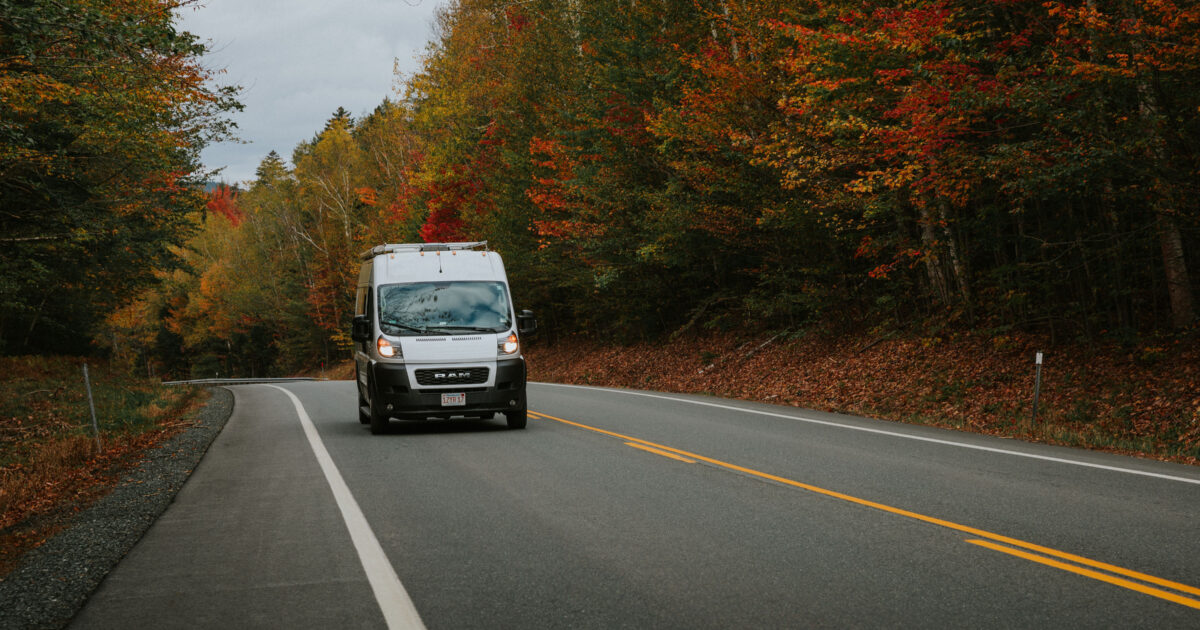 class B RV campervan on a road surrounded with fall foliage