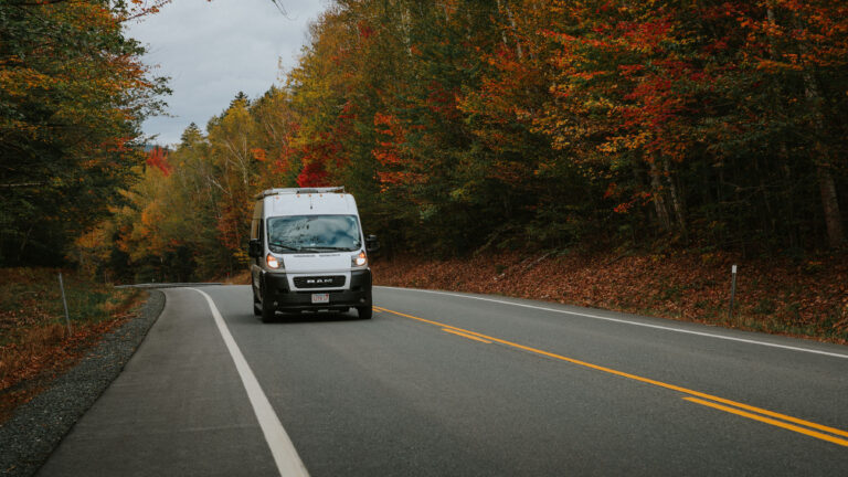 class B RV campervan on a road surrounded with fall foliage