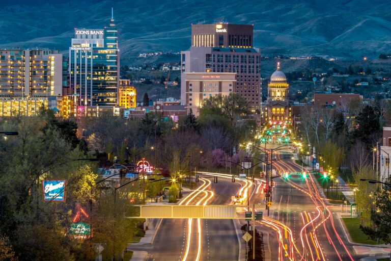 Downtown buildings lit up at night with mountains in the background