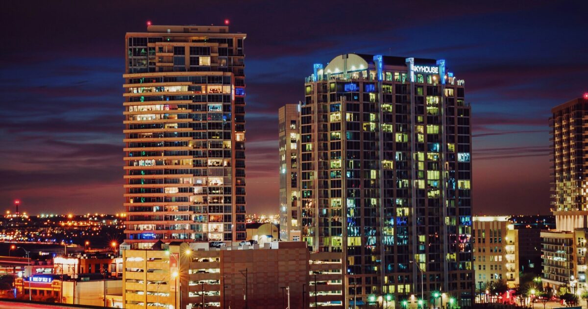 A freeway runs past lit-up downtown buildings at night