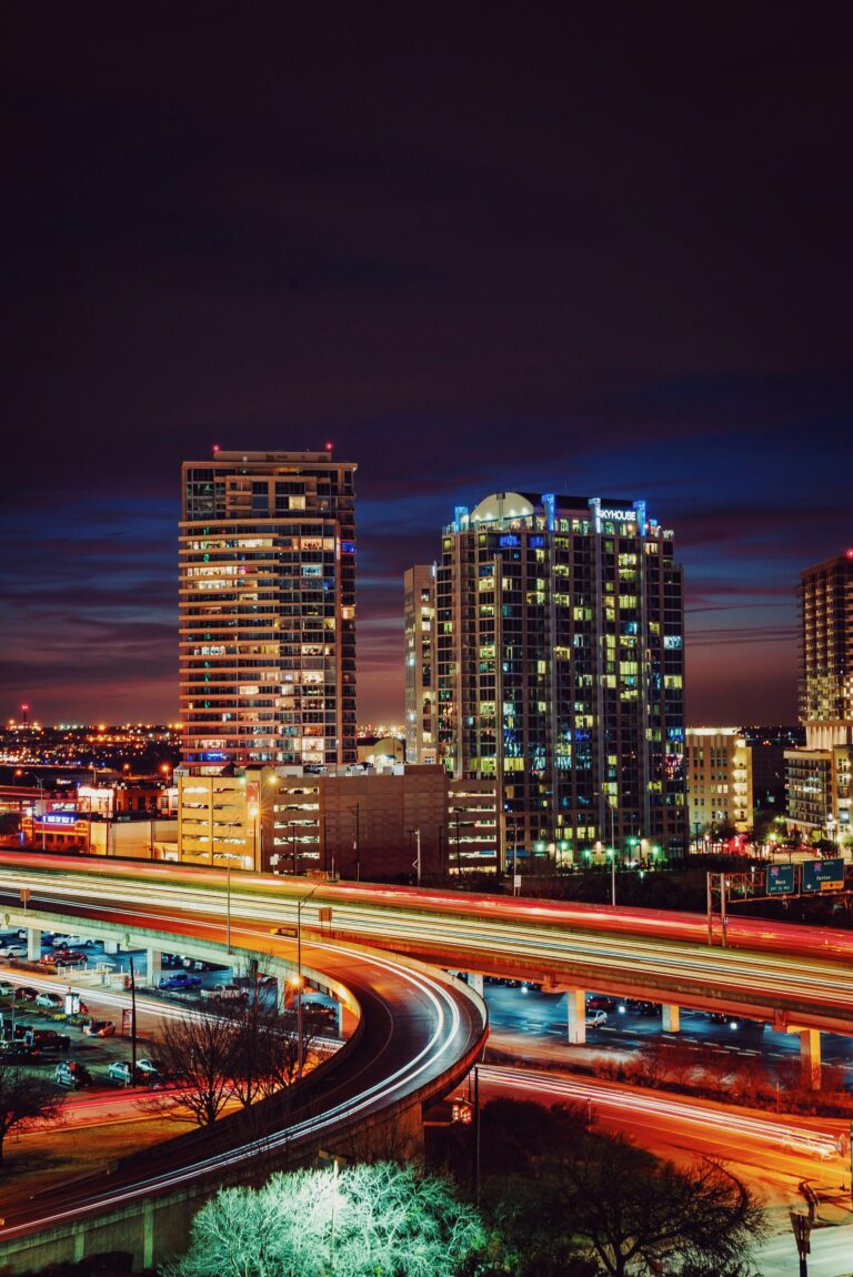 A freeway runs past lit-up downtown buildings at night