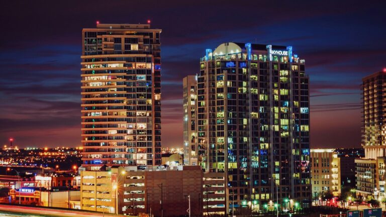 A freeway runs past lit-up downtown buildings at night